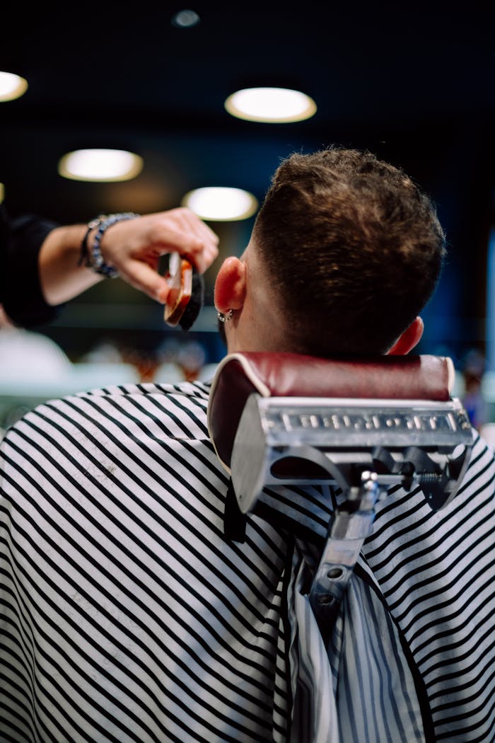 A man receiving a haircut at a barber shop in Geneva, Switzerland. Back view close-up.
