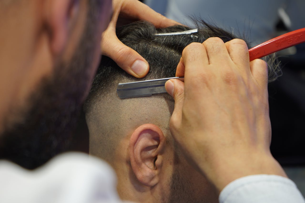 A close-up view of a barber shaving a mans hair with a straight razor.